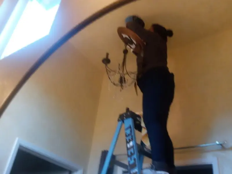 Electrician installing a chandelier in a Wilmington residence